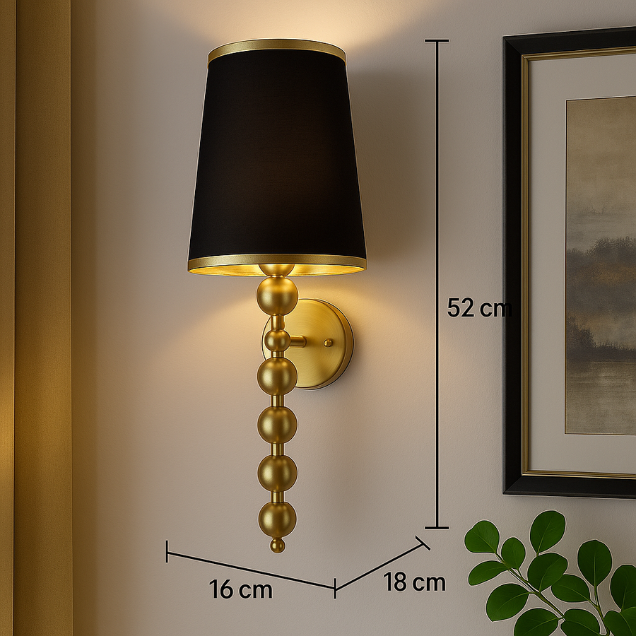 Wall sconce with black shade and gold base on a wall