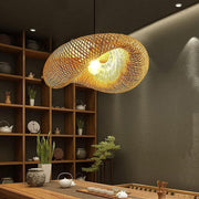 Woven pendant light hanging in a room with wooden shelves and decor items.